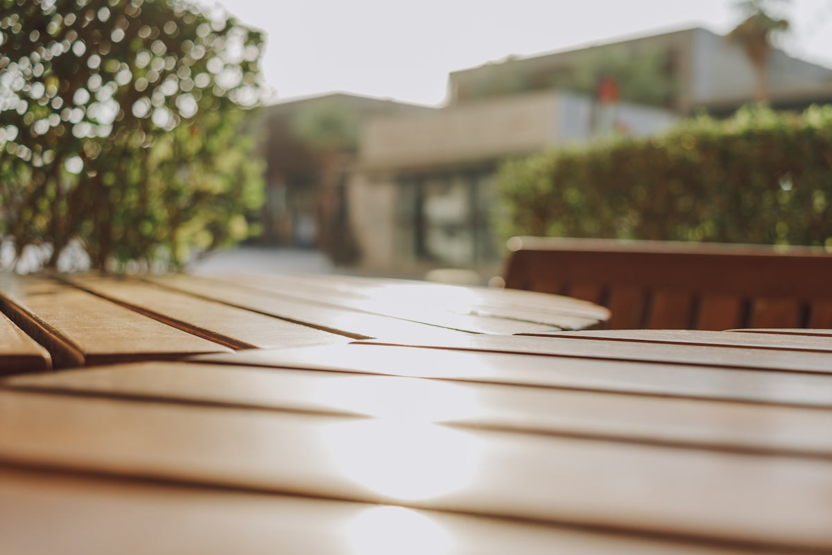 A close up of a wooden table with a building in the background