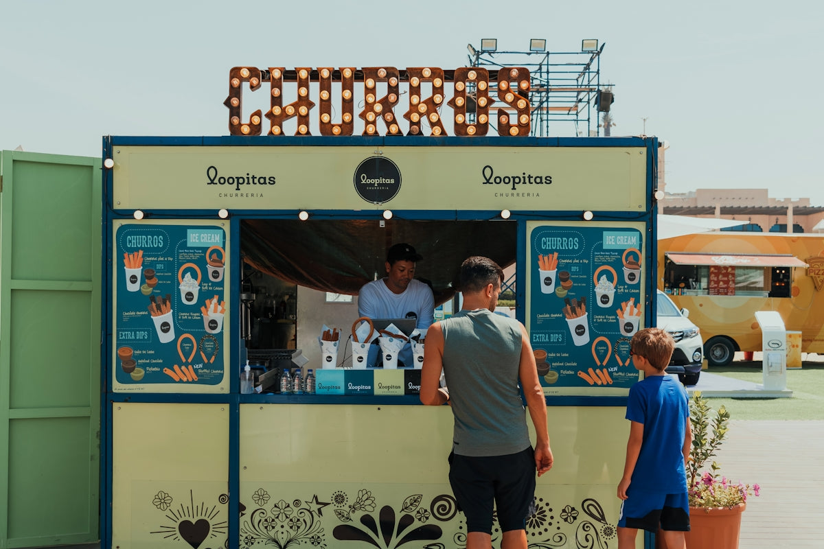 A couple of people standing at a food cart