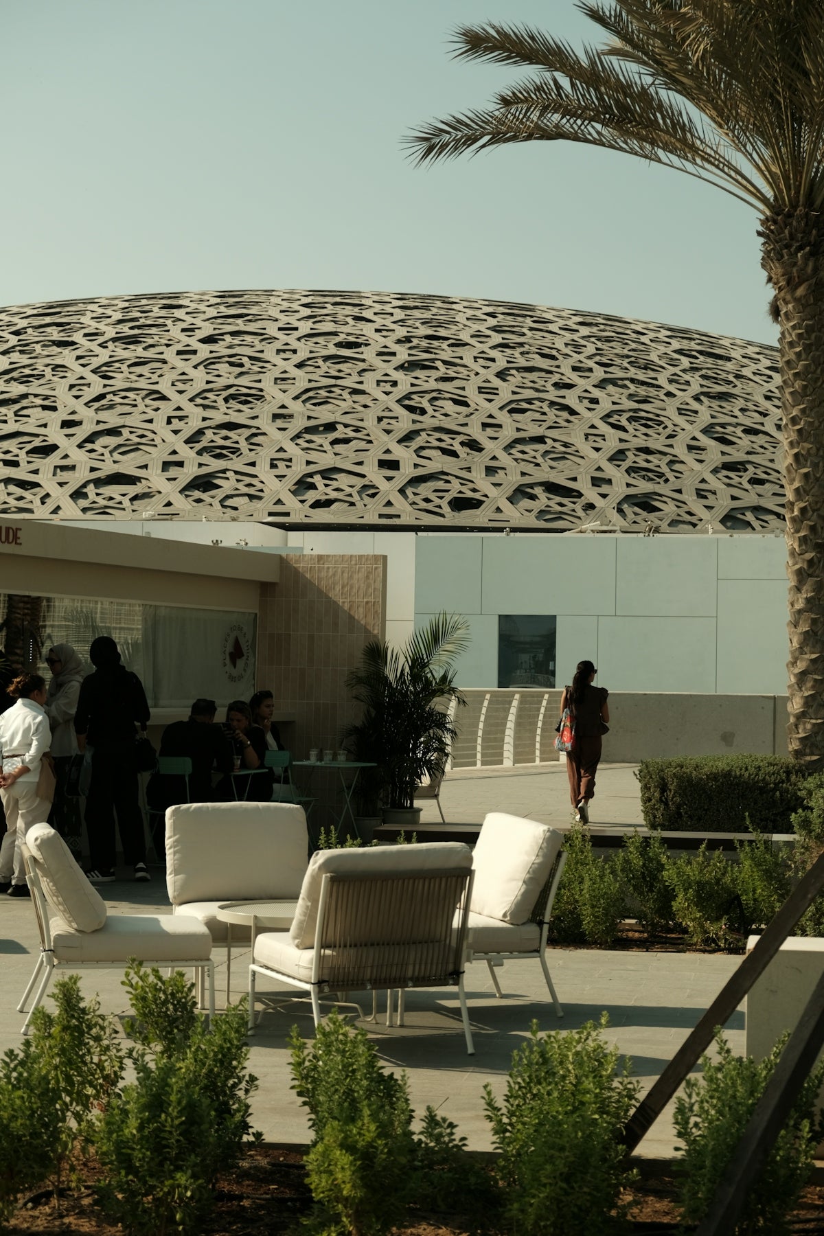 People relax at outdoor cafe near modern architecture
