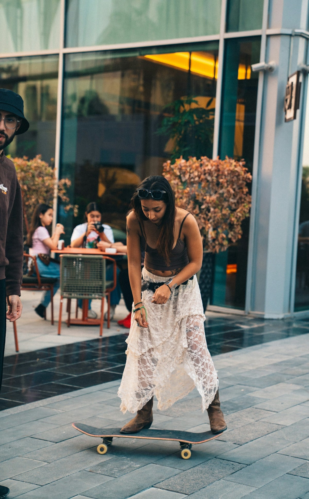 Woman in a white dress skateboarding on a paved area.
