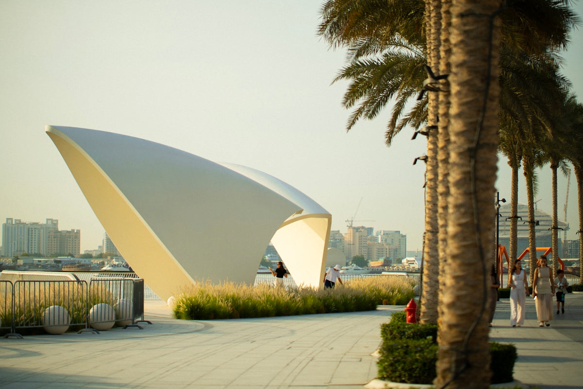 Modern white structure with palm trees and people walking