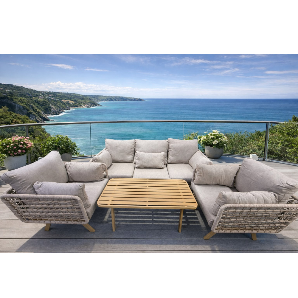 Modern grey wicker sectional sofa and wooden coffee table on a balcony overlooking the ocean at The Outdoor Furniture Market