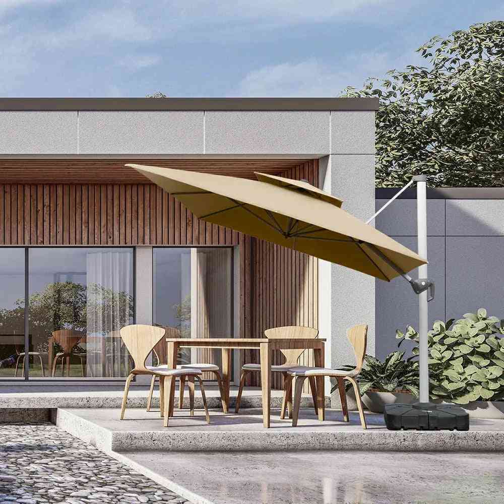 Beige outdoor umbrella over a dining table with chairs in front of a modern building.