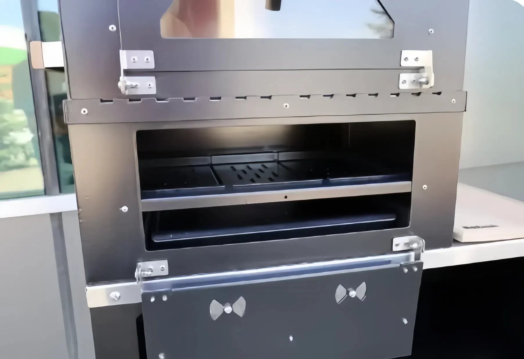 Casa Fiora charcoal pizza oven and BBQ grill with two storage levels, set in an outdoor kitchen setting.