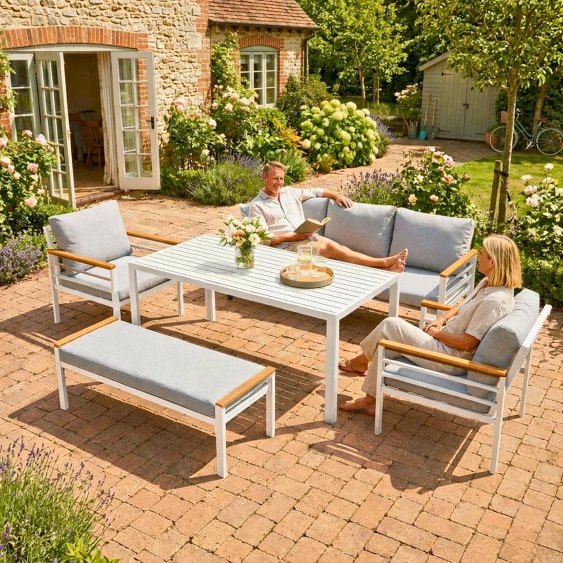 Seven-seater aluminium outdoor sofa and dining set with white frame, grey cushions, and slatted table for garden relaxation.